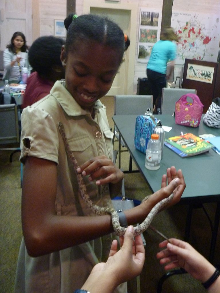 A SciGirl handles a rat snake.