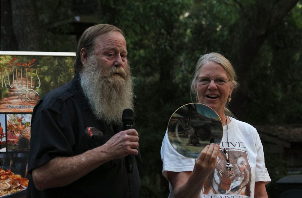 Robin Vroegop presents Mike Jones with a red wolf plate at the Red Wolf Revival screening at the Tallahassee Museum last Saturday, April 15. Robin thanked Mike for all of his help with Saint Vincent Island's red wolves over the years.