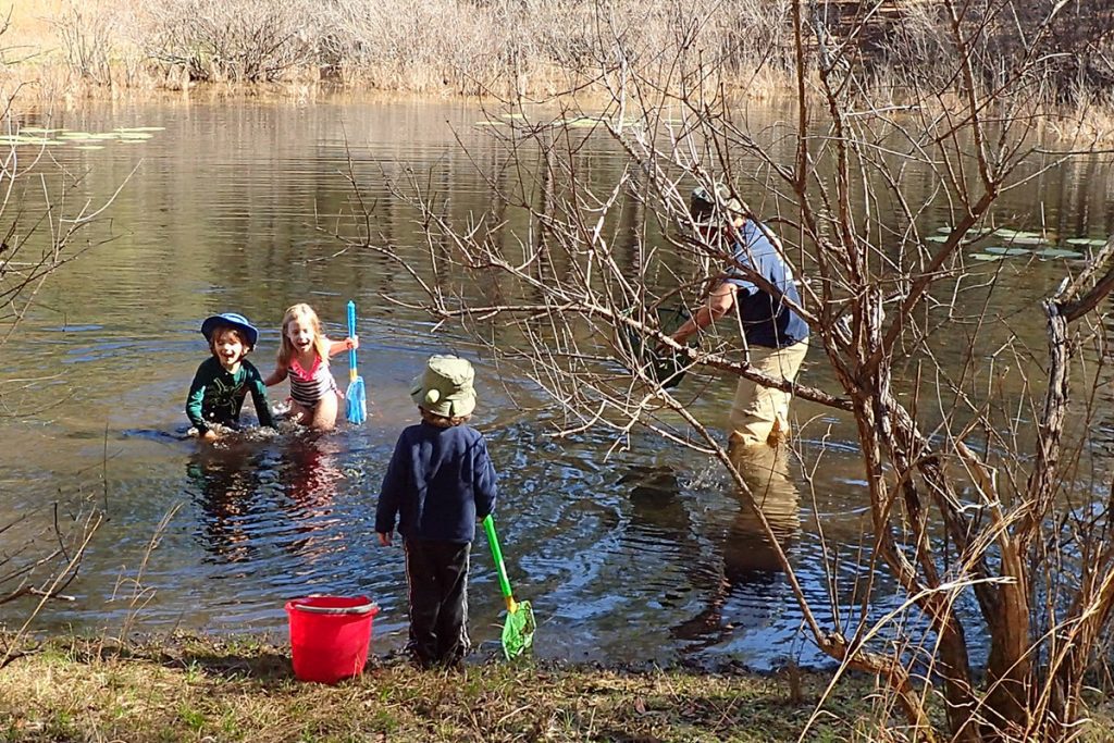 Kids play in an ephemeral wetland in the Munson Sandhills, filled with water.