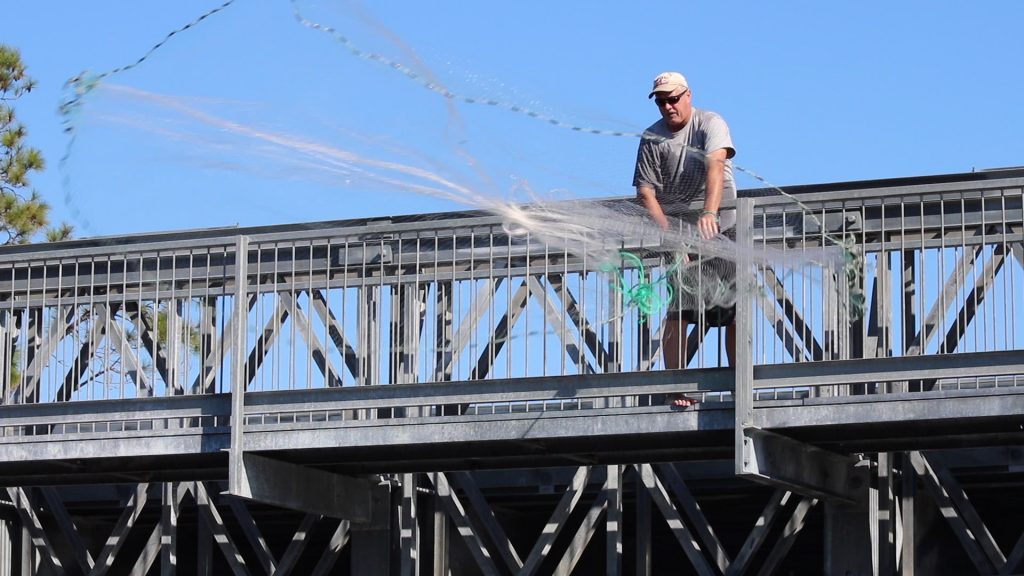 A fisherman casts a net off of the Chaires Creek Bridge in Bald Point State Park, hoping to catch mullet.
