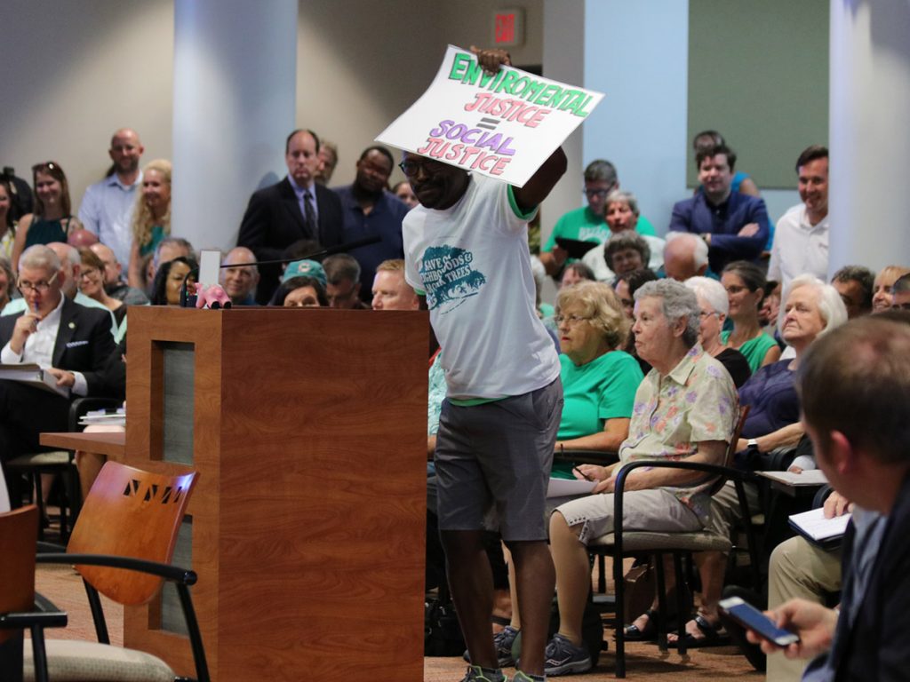 Stanley Sims holds up a sign that reads "Environmental Justice equals Social Justice" at a meeting of the Tallahassee/ Leon County Blueprint Intergovernmental Agency.