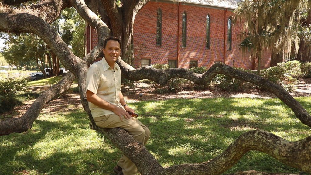 Jonathan Lammers, Historic Preservation Planner, sits on a live oak branch in Cherokee Park, one of Tallahassee's Chain of Parks.