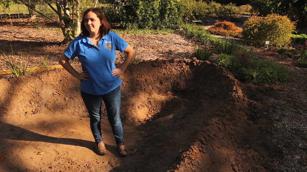 IFAS Horticulture Program Assistant Rachel Mathes stands in a dug out pond basin.