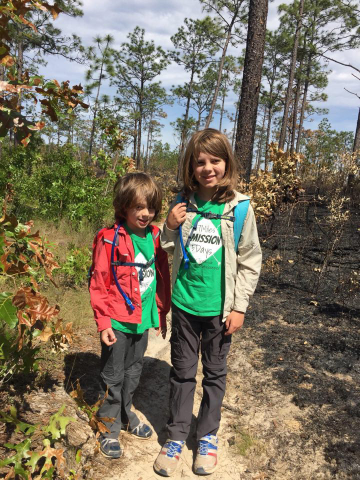 Xavi and Max stand on the Garden of Eden Trail.  One side of the trail has been recently burned, while the other has not.