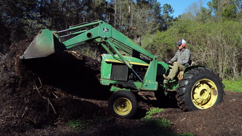 You may use a pitchfork or shovel to turn your home compost pile; Herman Holley uses a tractor to push his large piles of wood chips and seafood waste.