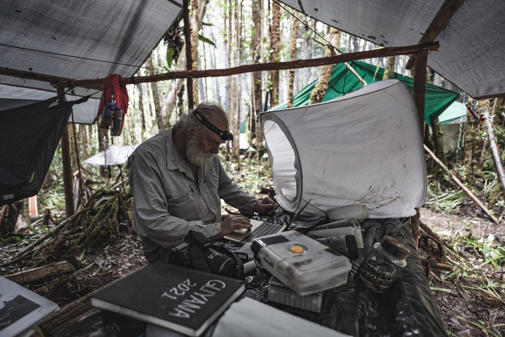 On his latest Guyana expedition, Bruce Means reviews his research in a makeshift tent.  Photo courtesy Renan Ozturk, Expedition Studios.