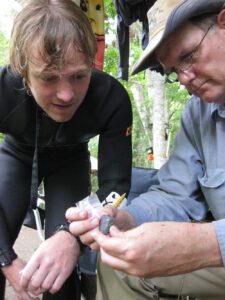 Morgan Smith (L) looks at a stone knife with Dr. Michael Waters, Director of the Center for the Study of the First Americans at Texas A&M University. The knife had just been found at the Page-Ladson site in Florida's Aucilla River. Photo courtesy Dr. Jessi Halligan.